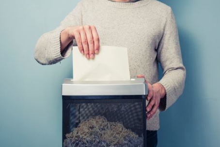 a person feeding a piece of paper into a shredder