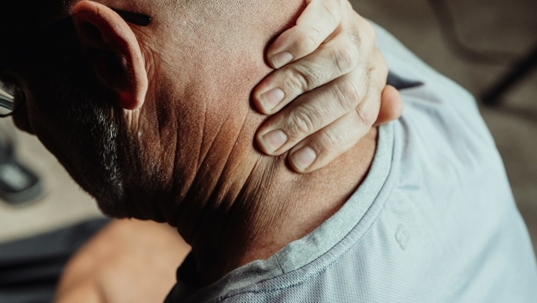 a man is holding his neck with an expression of discomfort