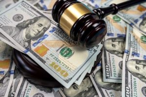 a wooden gavel resting on a pile of U.S. $100 bills.