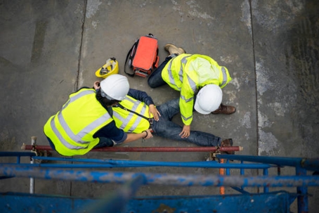 two individuals attending to a person lying on the ground, showcasing an emergency first-aid response.