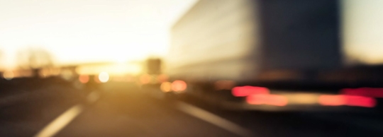 The image shows a blurred view of a highway at sunset.