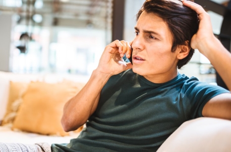 Man sitting on a couch making a phone call.