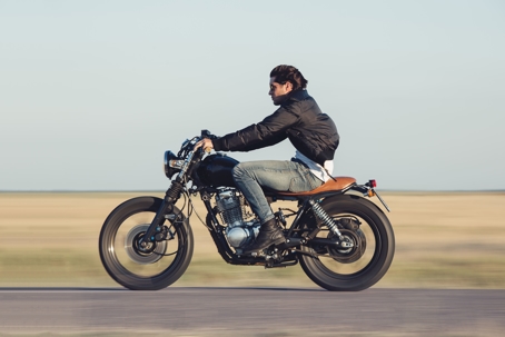 A rider leans slightly forward while navigating a motorcycle along a road.