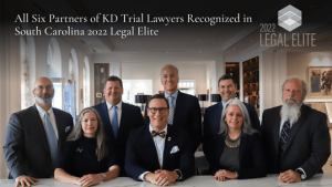 The image features seven formally dressed individuals in an office setting, highlighting that "All Six Partners of KD Trial Lawyers" were recognized in South Carolina's 2022 Legal Elite. A "2022 Legal Elite