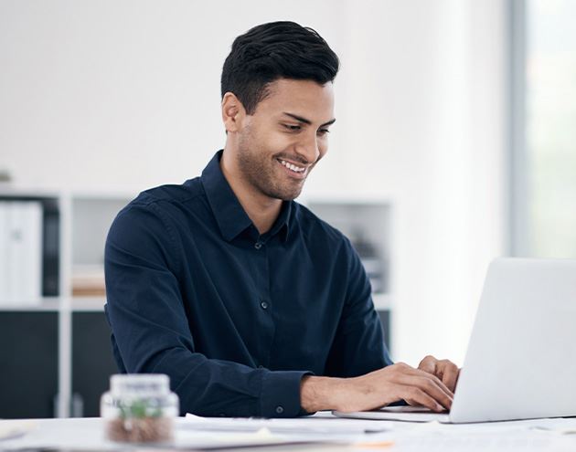 a person sitting at a desk and working on a laptop, their focus on typing or interacting with the device